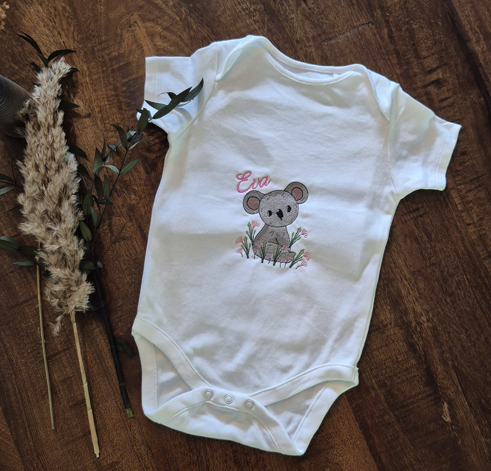 Witte babyromper met geborduurde koala, roze bloemetjes en voorbeeldnaam Eva